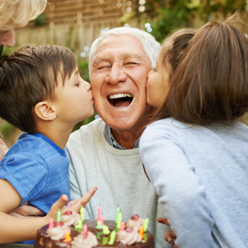 Two children kissing grandfather on cheeks | BCBS of Tennessee