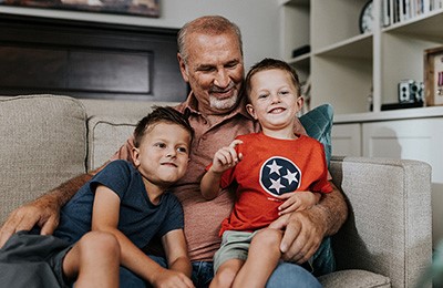 Grandfather sitting on a couch with his twin grandsons.