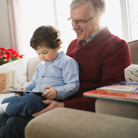 Kid sitting on man’s lap and looking at the tablet together | BCBS of Tennessee