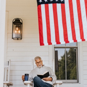 Older man sitting under an american flag