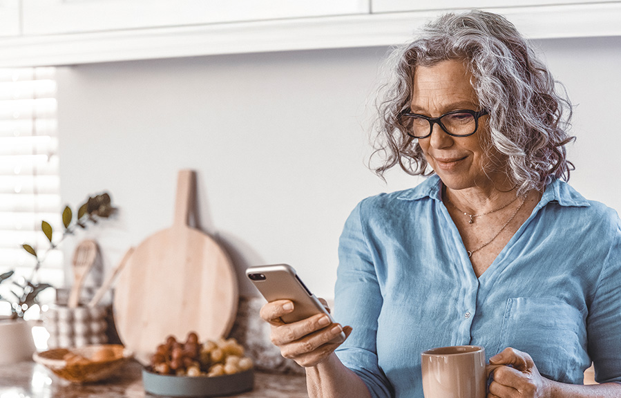 Woman scrolling on her mobile phone in her kitchen.