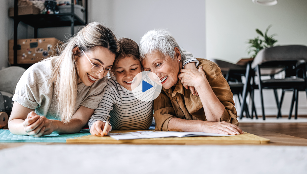 Mother, grandmother, and granddaughter on a play mat, coloring in a coloring book.