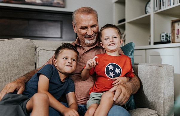 Grandfather sitting on a couch with his twin grandsons.