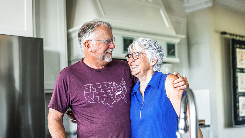Husband and wife laughing in their kitchen.