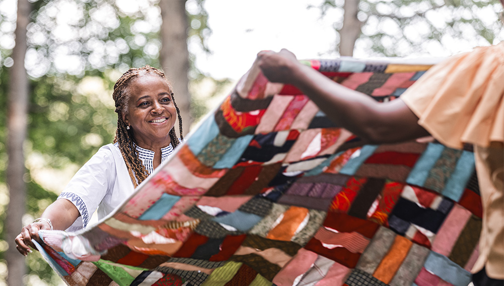 Mother and daughter spreading out a quilt.
