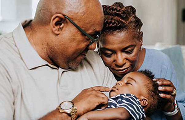 Grandparents holding their sleeping grandson.