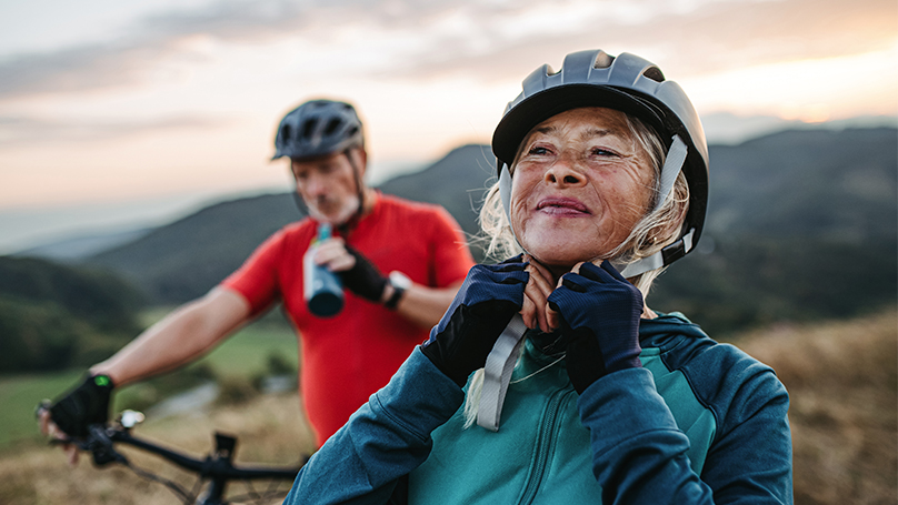 Wife adjusting her helmet on a bike ride with her husband. Wife adjusting her helmet on a bike ride with her husband.
