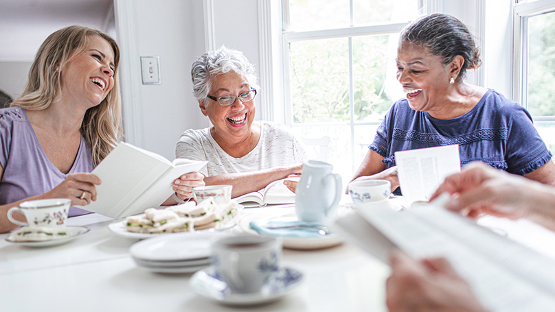 A group of older women enjoying conversation over lunch together.
