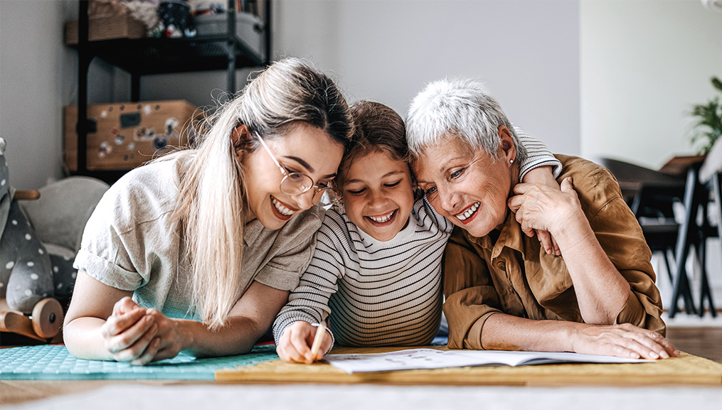 Child coloring on the floor with his mother and grandmother.