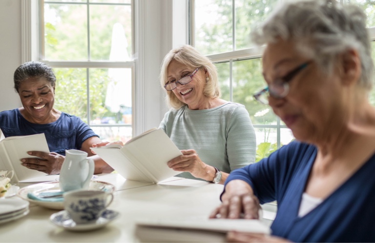 Three older women smiling and reading