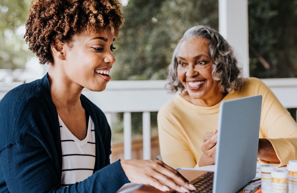 grandmother and granddaughter smiling at laptop
