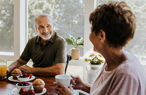 Older couple smiling over breakfast.