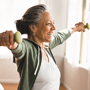 A senior woman using weights to workout her arms.